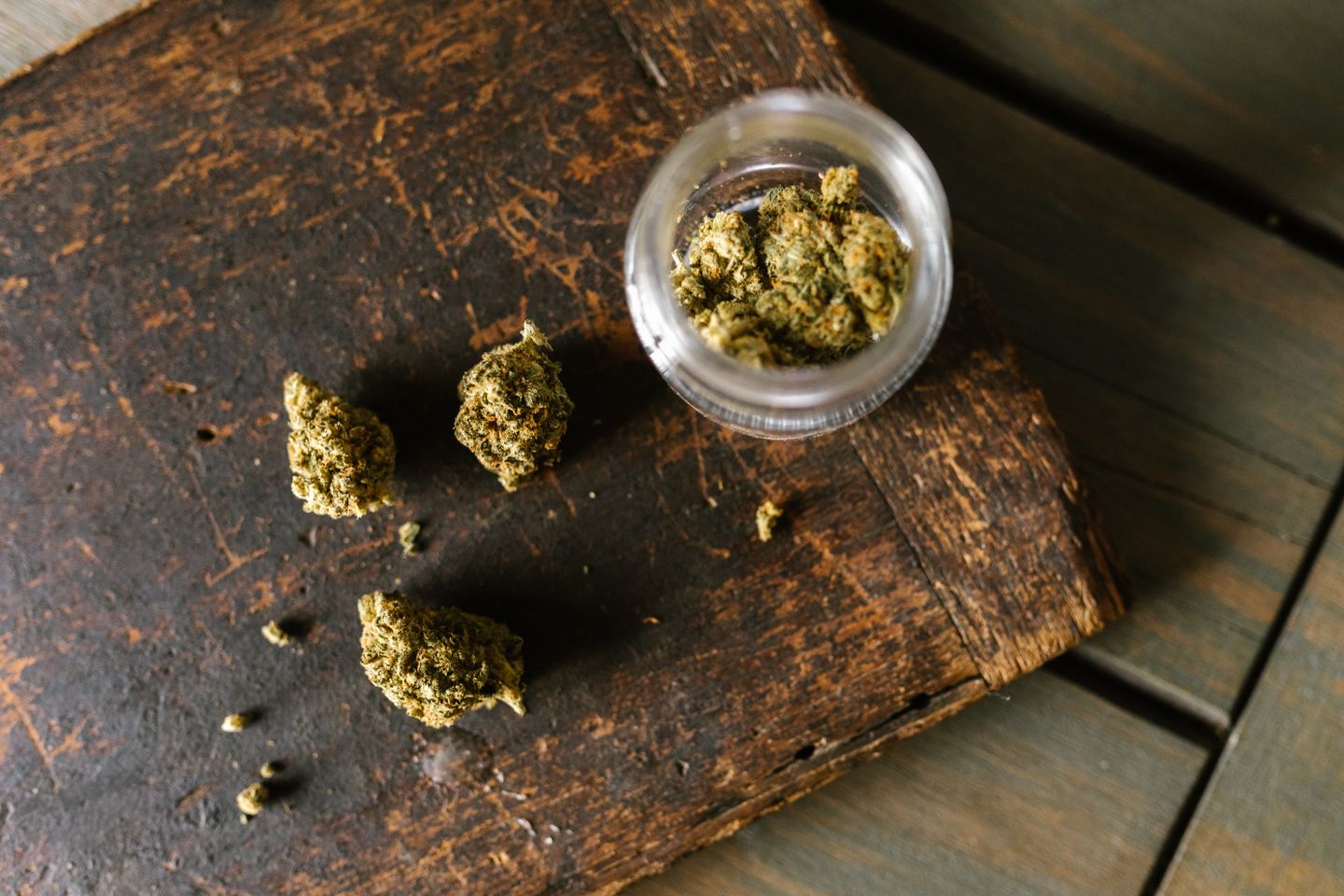 Fleurs de CBD en vrac et bocal en verre sur bois brut