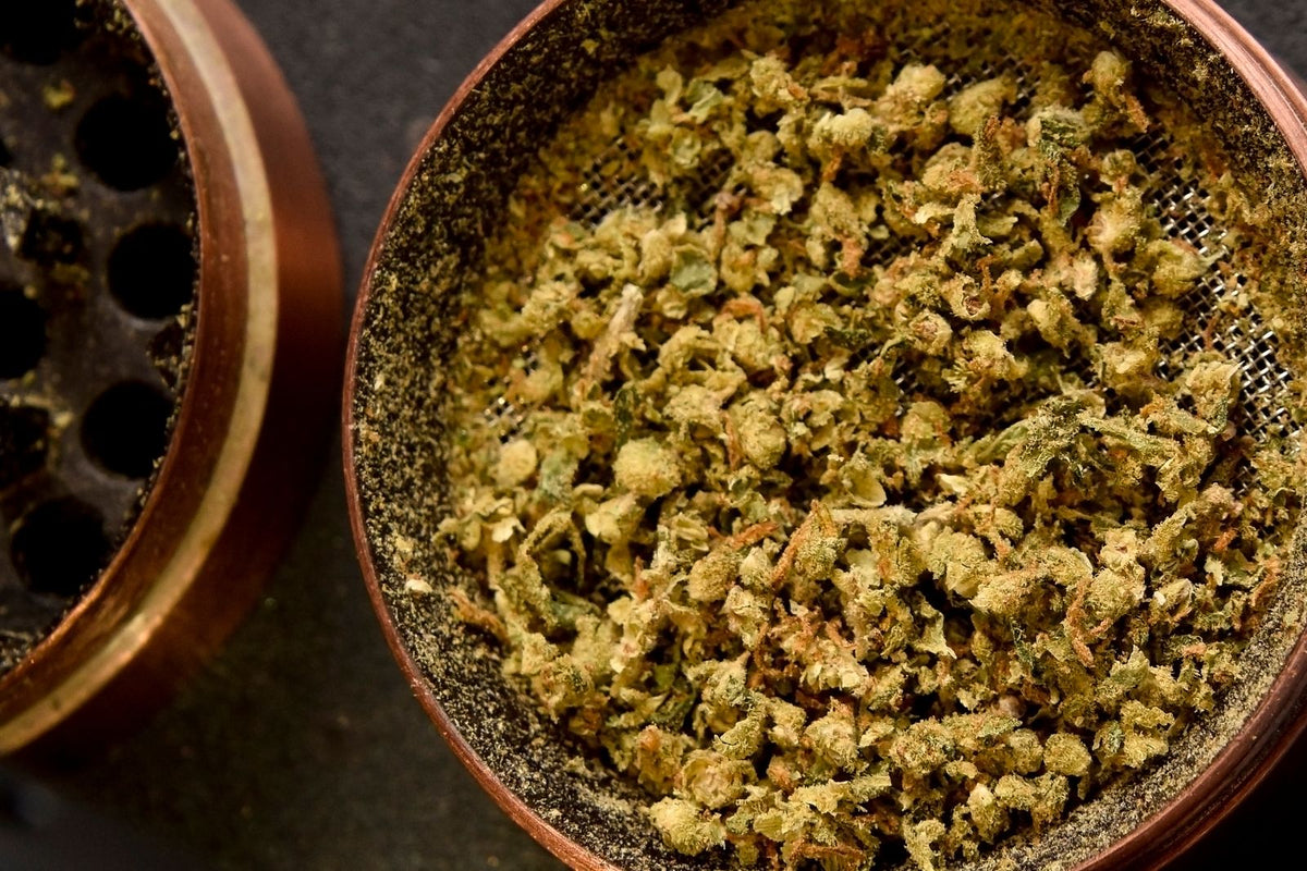 Fleur de CBD finement moulue dans un grinder en métal, vue de dessus : la mouture avant de remplir un vaporisateur